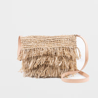Small light raffia handbag with fringing detail. Fully lined with inside pocket, adjustable leather shoulder straps and magnetic clasp closing. 