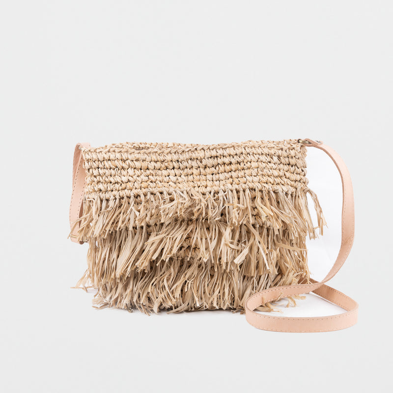 Small light raffia handbag with fringing detail. Fully lined with inside pocket, adjustable leather shoulder straps and magnetic clasp closing. 