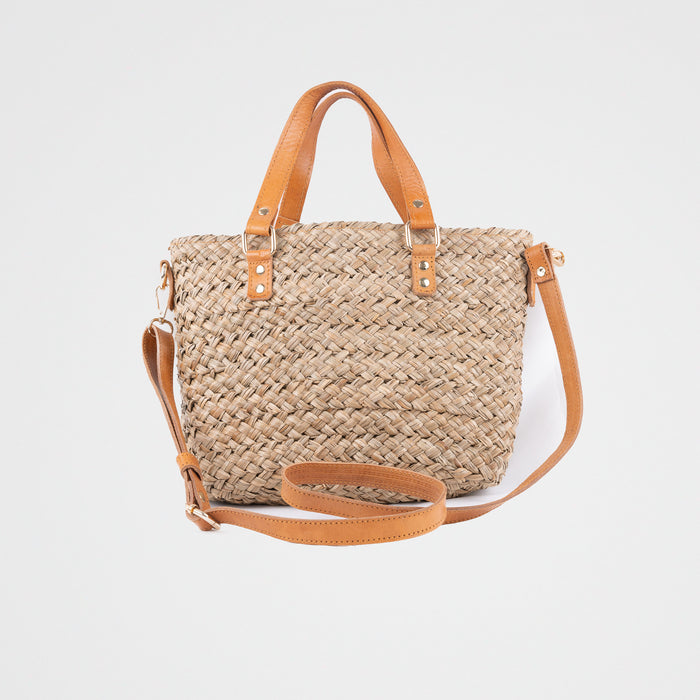 Seagrass natural handbag with adjustable tan leather shoulder straps and handles. Fully lined with a fabric pouch. Pull tie closing.