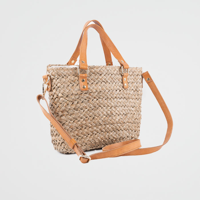 Seagrass natural handbag with adjustable tan leather shoulder straps and handles. Fully lined with a fabric pouch. Pull tie closing.