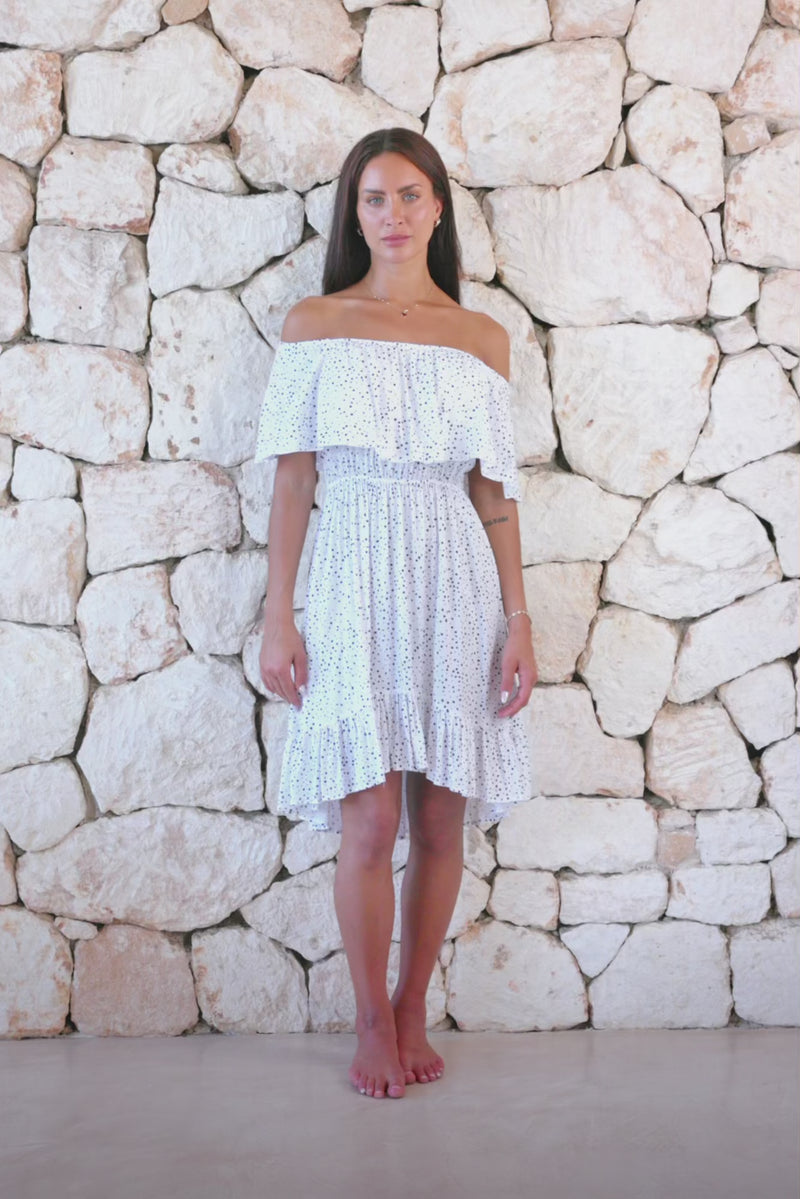 Womens elegant short length dress in white polka dot featuring an off the shoulder frill and elasticated waist