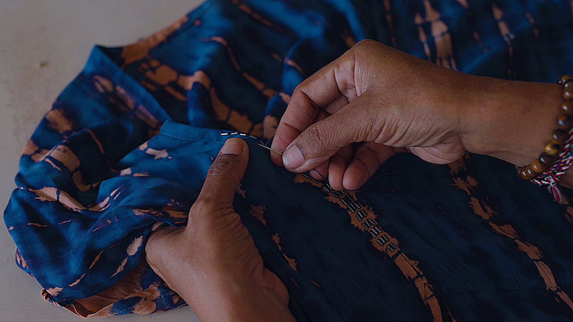 Balinese artisan tying Navy and Copper tie-dye fabric by hand in traditional workshop